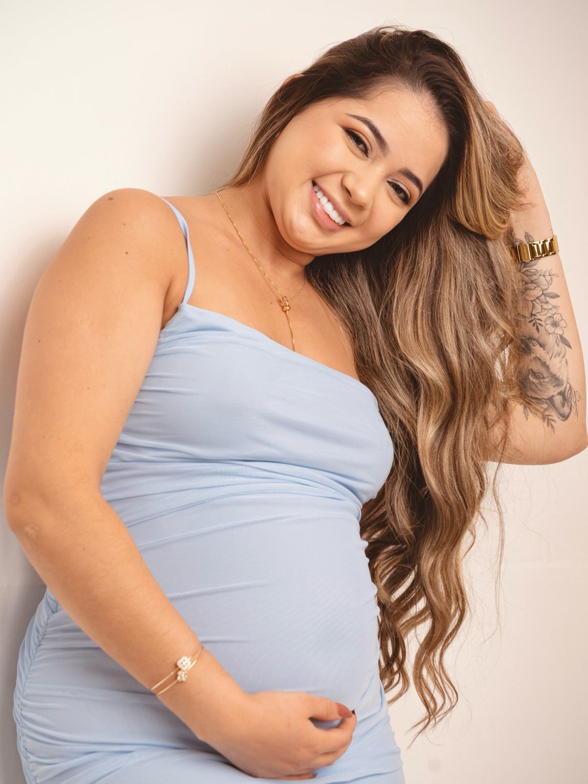 Gestante sorrindo em vestido azul-claro