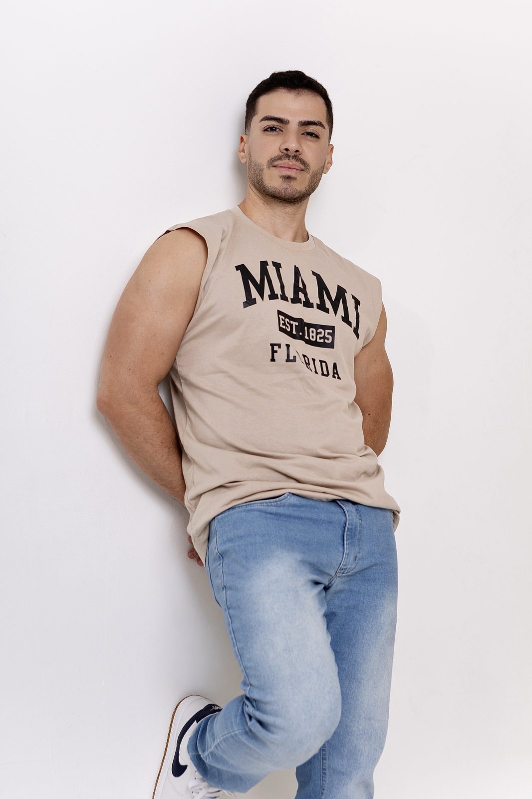 Homem em pose lifestyle com regata bege e calça jeans