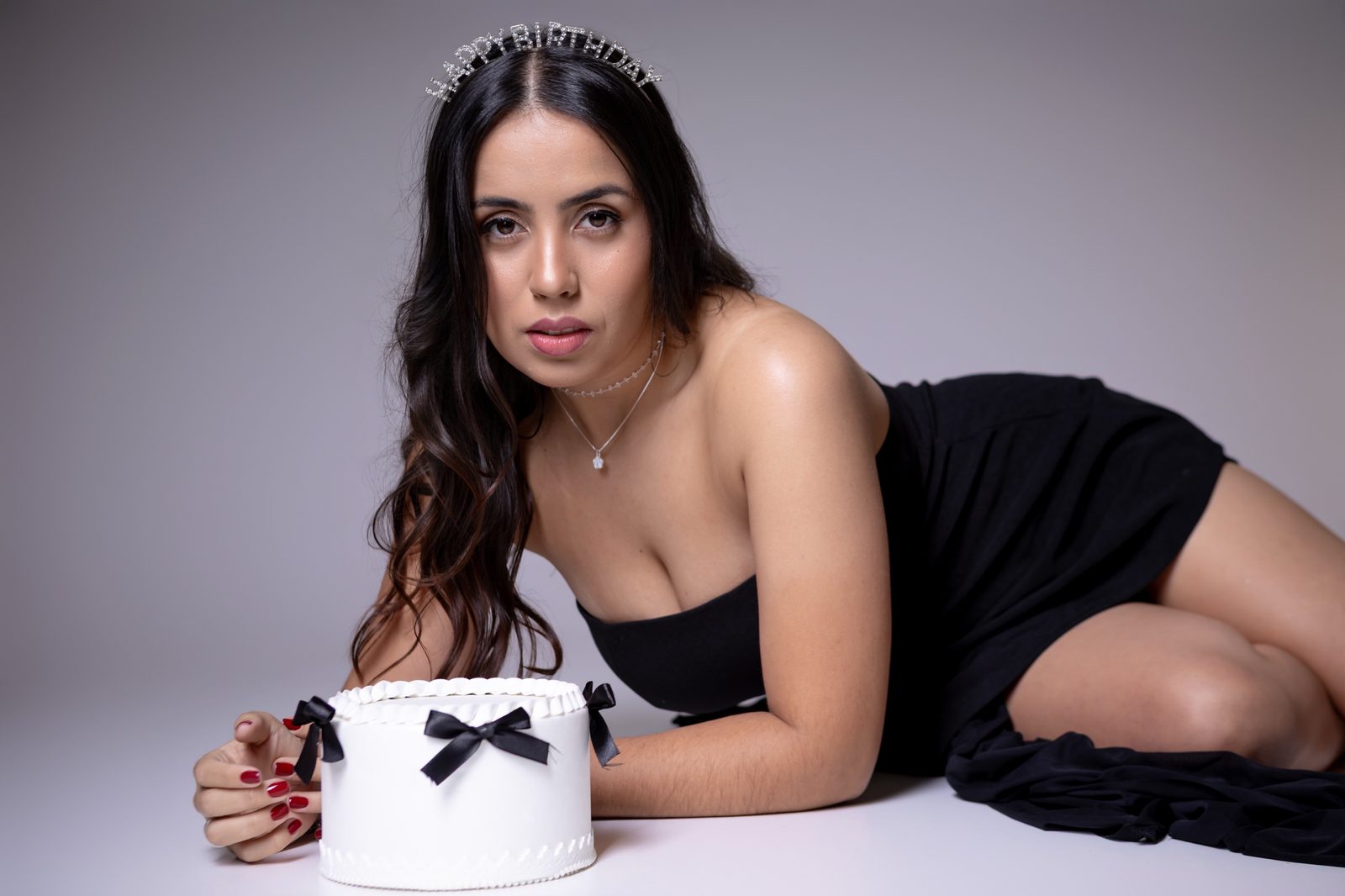 Mulher de vestido preto com bolo de aniversário e tiara