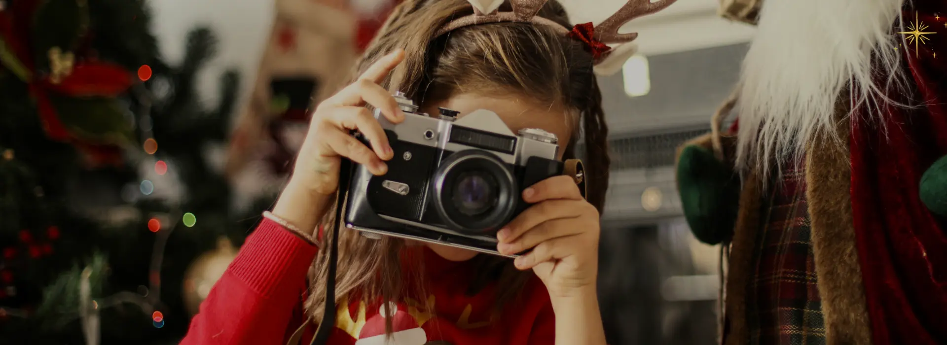 Criança com câmera fotográfica ao lado do Papai Noel em cenário natalino